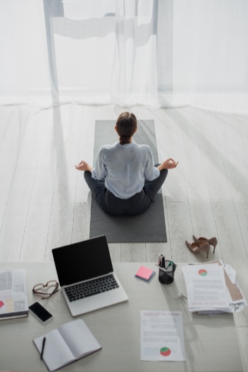 A business woman practising mindfulness on a yoga mat